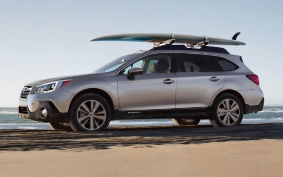Image of a 2018 Subaru Outback parked in front of the beach.