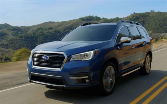 Image of a blue Subaru SUV driving on a country highway.