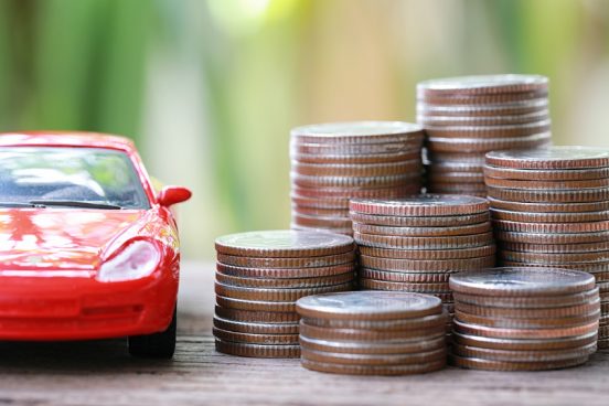 Image of a red toy car next to a stack of coins.