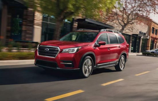 Image of a red 2020 Subaru Ascent driving down a city street.
