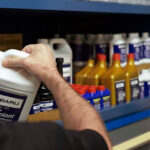 Subaru service technician grabbing a bottle of coolant from the shelf